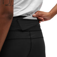 A person wearing dark ON Active tights putting their phone in the back pocket.