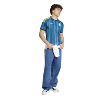 Person wearing a blue sports jersey with Adidas logo on a white background