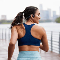 Woman running wearing Shokz OpenMove sports headphones in grey