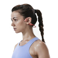Woman wearing Shokz OpenRun Pro running headphones in pink ready to exercise
