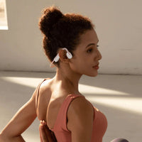 woman exercising using Shokz OpenMove sports headphones in pink